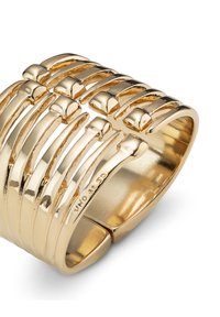 Anillo ancho dorado con múltiples líneas curvas y detalles redondeados, con una superficie pulida y detalles grabados en la banda interior.