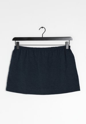 Falda de color azul marino con una cinturilla elástica, que presenta un patrón texturizado de líneas en espiral, colgada en una percha negra sobre un fondo blanco.