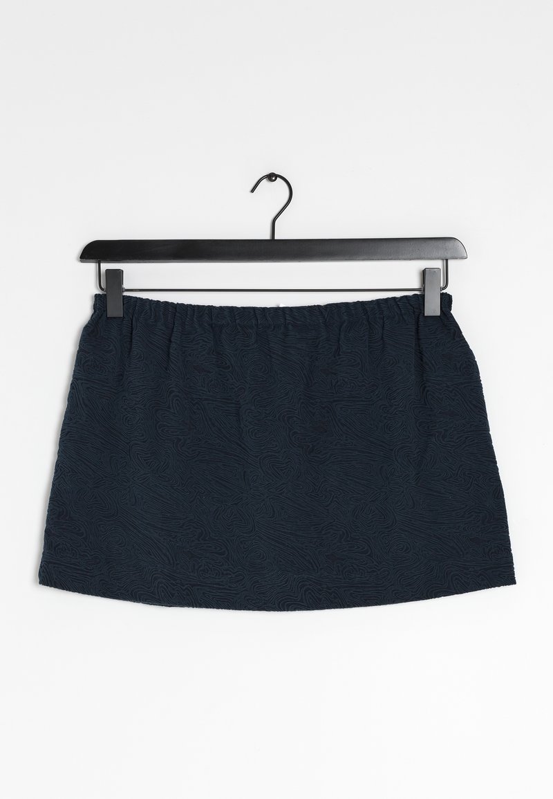 Navyblaue Rock mit elastischem Bund, der ein strukturiertes Muster aus wirbelnden Linien aufweist, hängt an einem schwarzen Haken vor einem weißen Hintergrund.