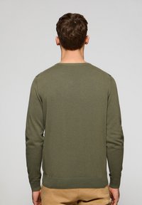 Suéter de manga larga verde oliva con cuello redondeado, puños y dobladillo acanalados. Fabricado en un suave material de punto, con una textura lisa.