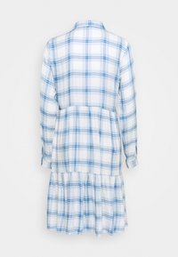 Abito bianco con motivo a quadri blu, maniche lunghe e polsini con bottoni; presenta una vita aderente e una ruffle raccolta all'orlo.