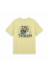 T-shirt di cotone giallo chiaro con design grafico di un'ape nera con occhi blu e la scritta "THE SWARM" in nero, su uno sfondo a spruzzi.