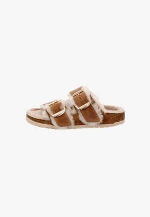 Brown suede slide sandal with two adjustable straps, fluffy white lining, and a textured cork footbed. Flat sole design for comfort.