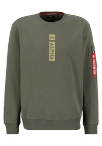 Sudadera verde oliva con cuello redondo. Presenta un logo frontal y un bolsillo con cremallera en la manga con una etiqueta roja. El material parece suave.