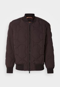 Blouson bomber matelassé marron foncé avec fermeture éclair à l'avant, poignets, col et taille côtelés, avec un motif de couture circulaire.