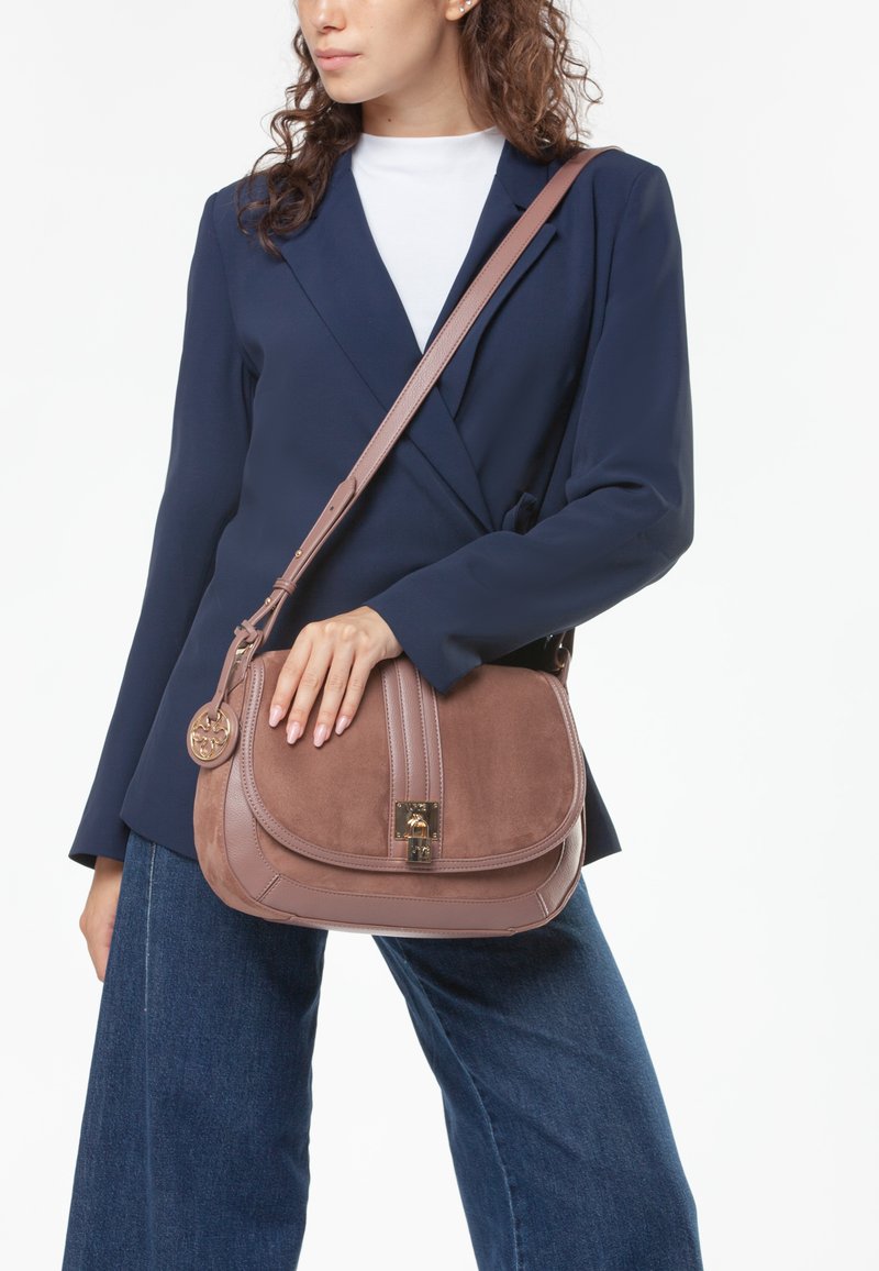 Borsa a tracolla in pelle scamosciata e cuoio marrone con hardware dorato, caratterizzata da una patta curva, impunture a contrasto e un charm decorativo. Strap regolabile.