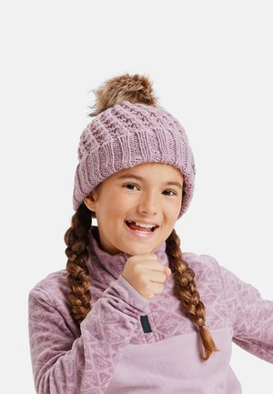 Knitted pink beanie with a large faux fur pom-pom, featuring a textured design. Child wears a matching fleece top with a patterned upper section.