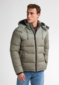 Jacheta puffer într-o nuanță verde estompată, cu un finisaj texturat, închidere cu fermoar, glugă ajustabilă și panouri pentru umeri de culoare verde deschis contrastantă.