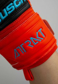 Czerwony rękawica sportowa z wyściełanym paskiem na nadgarstek z niebieskim napisem "ATRAYKT". Materiał syntetyczny z teksturowanymi akcentami i czarnymi detalami.