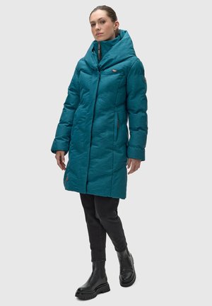 Teal puffer coat with a large collar, zip front, and side pockets. Features textured fabric and a slightly oversized fit. Black pants and boots complete the look.