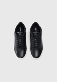 Sneakers negre din piele cu o talpă din cauciuc albă, vârf rotund, design cu șireturi și un logo pe lateral. Interiorul este căptușit cu negru.