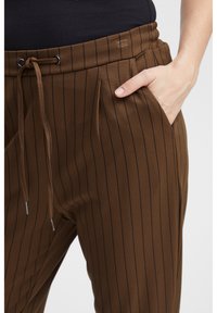 Bruine broek met pinstripe patroon, voorzien van een elastische tailleband en een trekkoord. Heeft zijzakken en een gladde, gestructureerde stof.