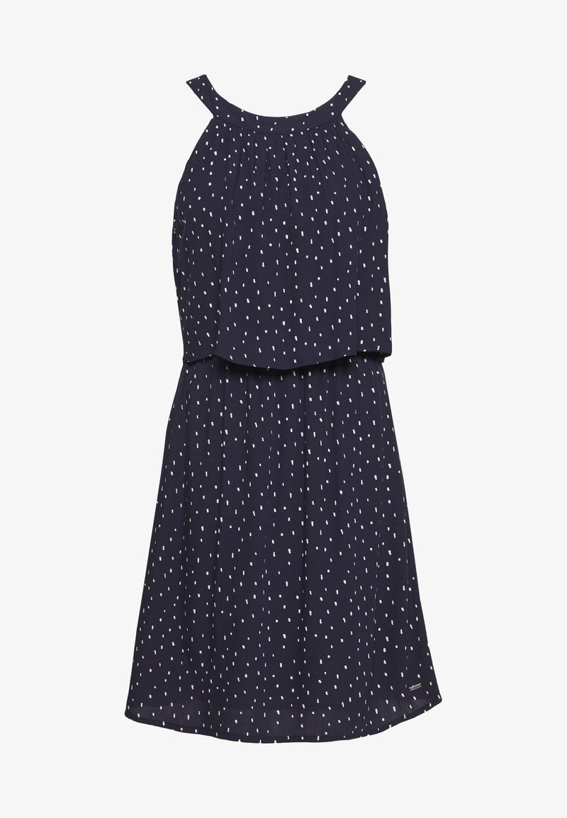 Robe bleu marine sans manches avec motif à pois blancs, encolure froncée et haut superposé sur une jupe évasée.