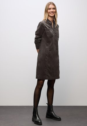 Dark gray corduroy shirt dress with a collar, long sleeves, front pocket, and above-the-knee hem. Paired with ankle boots.