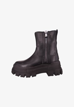 Botas de tornozelo em couro preto com sola robusta, fecho lateral em zip, textura suave e design minimalista. Apresentam uma sola de borracha espessa com cravos.
