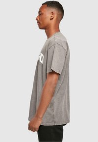Grijze katoenen t-shirt met een relaxed fit, verlaagde schouders en witte print. Heeft een vervaagde textuur en een licht oversized ontwerp.