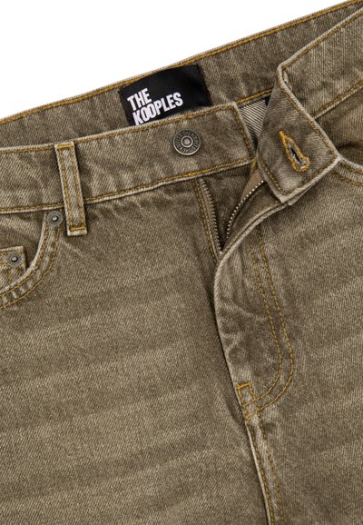 Jeans de mezclilla khaki con costuras amarillas, cierre frontal con cremallera y botón. Presenta la etiqueta de marca "THE KOOPLES" en el interior de la cinturilla.