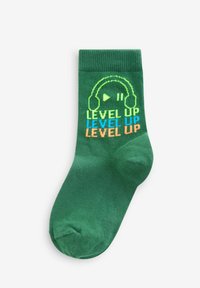 Grøn bomuldsstrømpe med ribbet top, der har en høretelefongrafik og teksten "LEVEL UP" i blå og orange. Glat overflade, længde til midt på læggen.