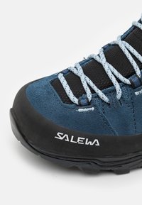 Blue suede hiking shoe with black mesh and rubber accents. Features light blue laces and "SALEWA" branding on the side. Curved, textured sole.