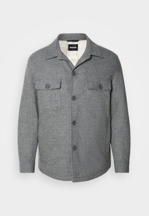 Giacca in misto lana grigia con chiusura a bottoni, due tasche sul petto e colletto a punta. Presenta una fodera interna liscia e bottoni neri.