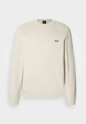 Krēmkrāsas džemperis ar apaļu kakla izgriezumu, teksturētu audumu, ribotām aprocēm un apakšu. Krūšu rajonā ir melns "BOSS" logotips.