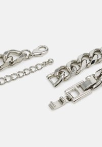 Pulsera de cadena de metal plateado que presenta segmentos enlazados, un cierre de langosta y un cierre de hebilla plana con superficies planas y bordes redondeados.