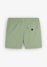 Shorts de bain vert clair en tissu texturé, avec une taille élastique et une poche arrière dotée d'un rabat et de détails en bouton.