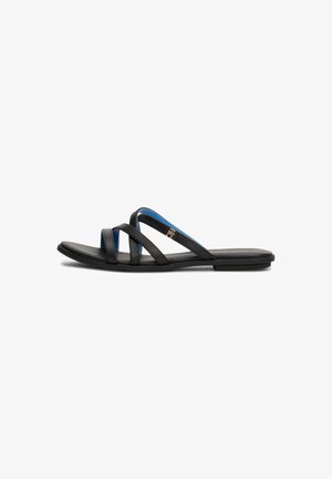 Sandalias planas negras con correas cruzadas que presentan un acento azul y un sutil detalle de logo. El material parece suave y flexible.