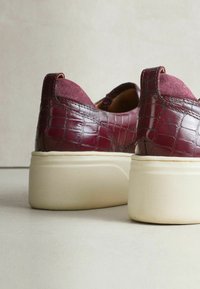 Bordeaux læder sneakers med krokodille tekstur, kontrasterende ruskindsaccenter og en tyk cremefarvet sål. Lavtop design med afrundet form.