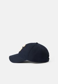 Gorra azul marino hecha de algodón, con una visera curva y dos parches de color claro en la parte frontal como acentos de diseño.
