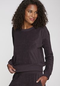 Temno purpurno sweatshirt iz mehkega blaga, z okroglim izrezom, dolgimi rokavi in širokim rebrastim robom.