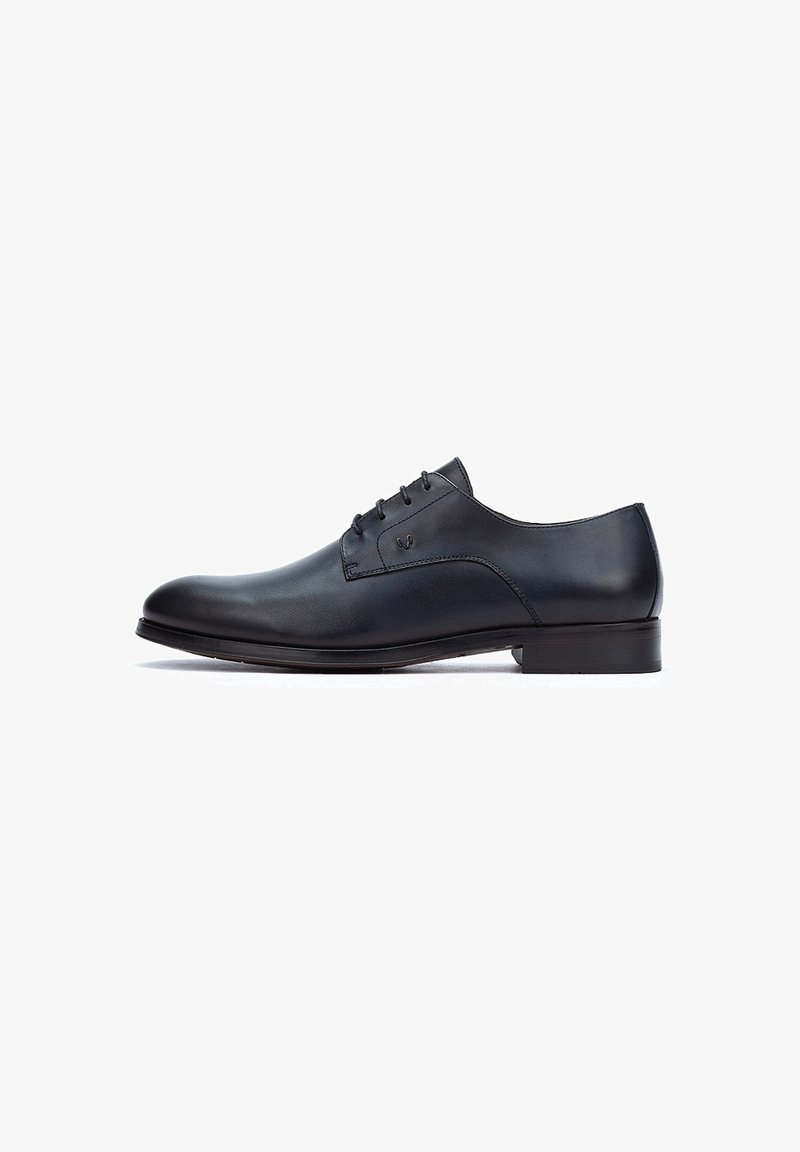 Chaussure habillée noire en cuir avec une finition lisse, bout rond, cinq œillets et un petit talon. Design simple avec des accents minimalistes.