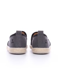 Scarpe slip-on in tela grigia con suole in juta intrecciata, dotate di un linguetta sul retro e un discreto logo vicino al tallone.