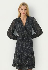 Rochie neagră cu model de puncte aurii, design înfășurat, mâneci lungi cu volane, talie elastică, tiv franjurat, fabricată dintr-un material ușor și transparent.
