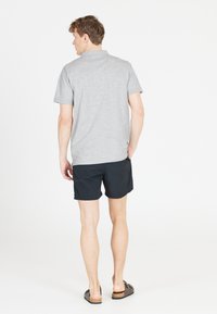 Grå kortärmad polotröja, blandning av bomull, med en avslappnad passform. Matchad med svarta badshorts och bruna sandaler. Enkel design.