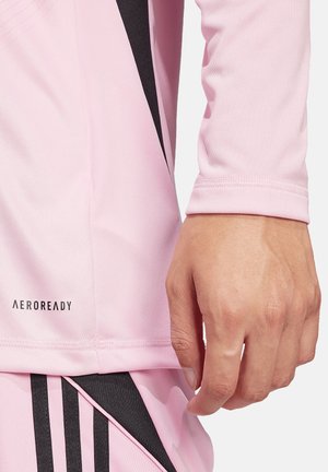 Aeroready langetermijnshirt in lichtroze met zwarte accenten. Glad textuur, aansluitend ontwerp en geborduurd merklogo nabij de zoom.