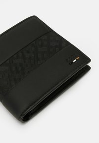 Portofel bifold din piele neagră, cu un model geometric texturat și logo-ul embosat "BOSS", având dungi negre, albe și maro în colț.