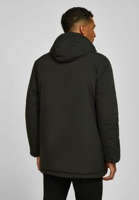 Zwarte, gebreide pufferjack met een lange snit, met een gladde textuur en elastische manchetten, geschikt voor koud weer.