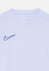 Hele lilla Nike Dri-FIT sportlik särk, millel on sinine tikk-kontuurlogo, ümmargune kaelus ja sile pind lühikeste varrukatega.