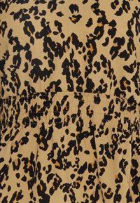 Il tessuto con stampa leopardata presenta uno sfondo beige con macchie nere e marroni. Il capo ha un dettaglio in vita arricciato.