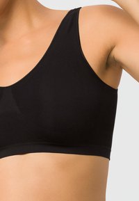 Schwarzer Stretch-Baumwoll-Bralette mit glatter Textur, breiten Trägern und einem stützenden Bündchen. Keine sichtbaren Verschlüsse oder Bügel.