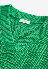 Grüner gestrickter Pullover mit V-Ausschnitt, geripptem Kragen und strukturierter Stoffqualität. Etikett mit der Aufschrift "NEXT" sowie dem Herkunftsland.