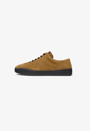 Sneaker in suede marrone con suola in gomma nera, caratterizzato da un design a taglio basso e lacci neri sui lati. Branding discreto sul tallone.