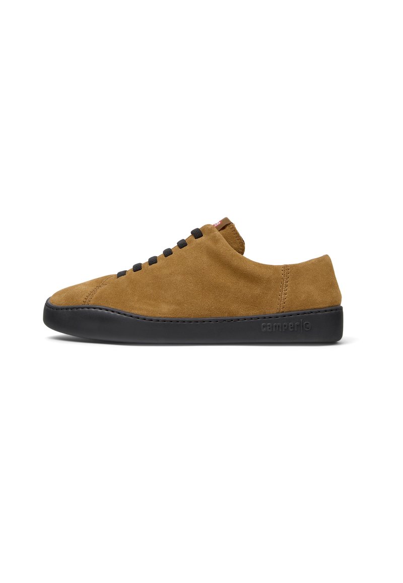 Zapatilla de ante marrón con suela de goma negra, que presenta un diseño de corte bajo y cordones negros a los lados. Marca sutil en el talón.