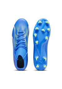 Scarpini da calcio blu con una parte superiore texturizzata, un motivo dinamico e un design leggero. La suola presenta tacchetti gialli per la trazione.