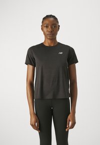 T-shirt de sport noir à manches courtes avec un col rond et un tissu texturé, arborant un petit logo gris sur la poitrine gauche.