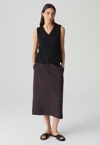 Haut sans manches noir avec un décolleté en V et une texture côtelée, associé à une jupe midi gris foncé avec deux poches avant et une coupe droite.