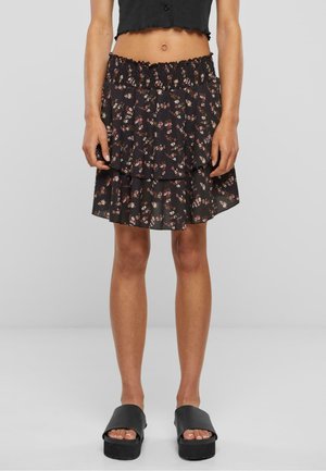 Black floral layered skirt with a smocked waistband and ruffled edges, featuring small pink and white flowers against a dark background.