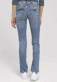 Jean en denim bleu clair avec une coupe slim, jambes droites et un léger délavage. Présente deux poches arrières et une taille mi-haute.