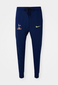 Marineblå sweatpants med et broderet logo på den øverste venstre lår og en lille gul Nike-swoosh på den nederste højre lår.
